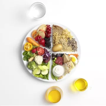 Teller mit Gemüse, Obst, Getreide, Hülsenfrüchten und Fleisch auf weißem Hintergrund