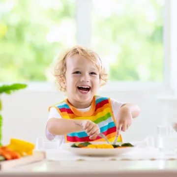 Lachendes Kleinkind beim Essen
