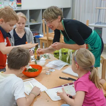 Kinder und Erwachsene beim Kochen.