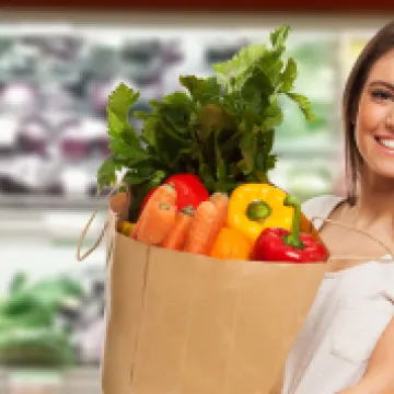 Frau im Supermarkt trägt ein Einkaufssackerl mit Gemüse darin © Minerva Studio / stock.adobe.com